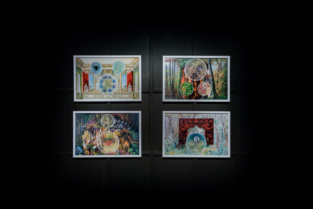 Four framed photographs in a grid formation on a black wall. Each composition features baroque wallpaper collages featuring petri dishes, and illustrations of cells.