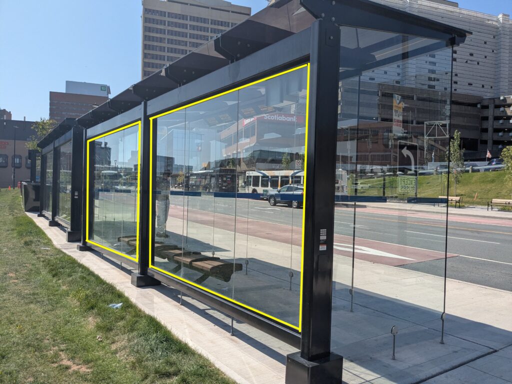 Image of the Transit Terminals from the back of the terminal shelter. The image has a yellow outline that covers the 6 panes of glass which are available for artists to design artwork for.